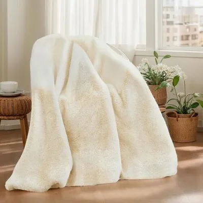 A plush blanket draped over a chair next to a window with plants.