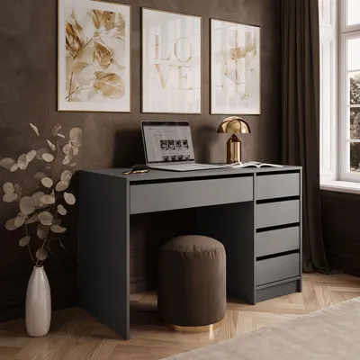 A modern desk setup with a laptop, lamp, and artwork on the wall.