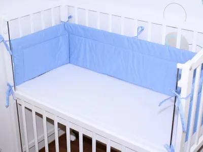 A close-up view of a baby crib with a blue bumper pad.