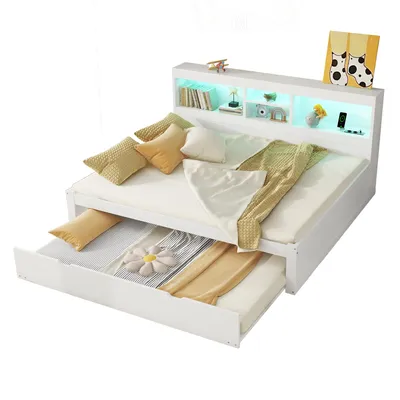 A white daybed with a pull-out trundle bed, decorated with pillows and blankets. The headboard has built-in shelves with LED lighting.