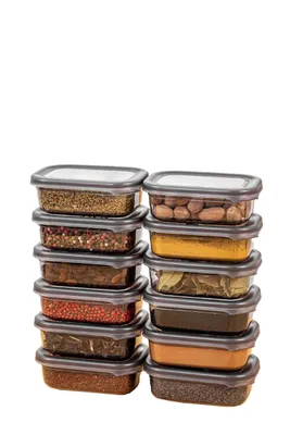 A set of 12 clear plastic food storage containers filled with various spices and grains, stacked in two columns against a white background.
