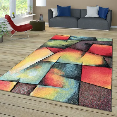 A modern living room with a geometric rug on a wooden floor.