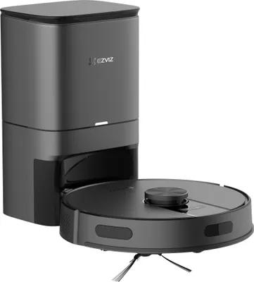 A dark gray robot vacuum cleaner docked in its charging and emptying station, presented on a white background.