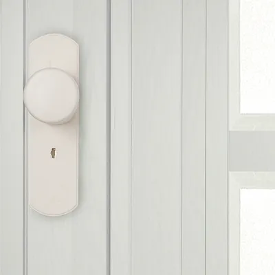 A close-up of a white door handle and lock on a white paneled door.