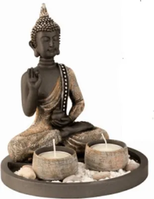 Eine Buddha-Statue, die auf einer runden Schale sitzt, die mit Kerzen und Steinen verziert ist.