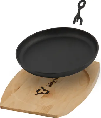 A cast iron serving pan with a wooden base and a small fork.