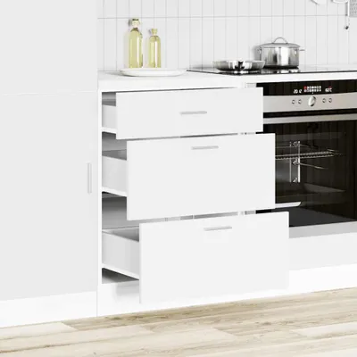 A modern kitchen scene with white cabinets and drawers, an oven, and kitchenware on the counter.