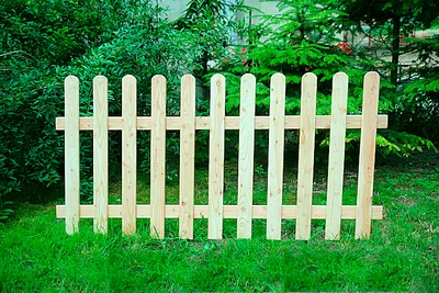 A wooden fence in a garden setting with green grass and trees in the background.