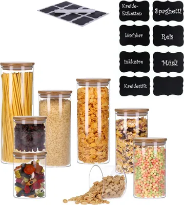 A collection of glass storage jars filled with various food items, along with a sheet of chalkboard stickers and individual chalkboard labels.