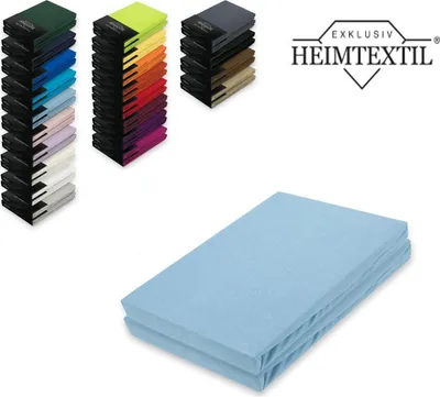 A stack of folded light blue bed sheets is shown in the foreground, with a display of various colored fabric swatches and a logo in the background.
