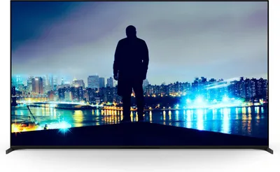 A person stands on a platform overlooking a city skyline at night.