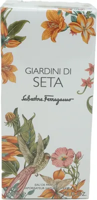 A close-up of a perfume box with floral and bird illustrations.
