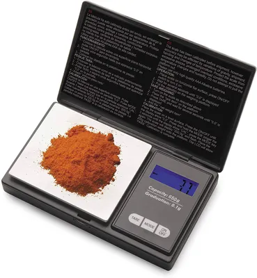 A digital scale with a pile of orange powder on its weighing platform.