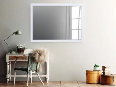 A mirror is displayed above a desk with a chair and decorative items in a room.