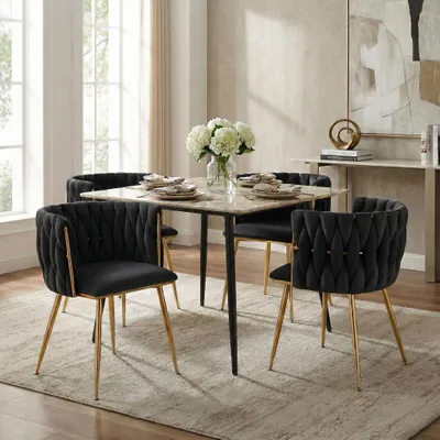 A dining room set with a marble-topped table and four black velvet chairs with gold legs.