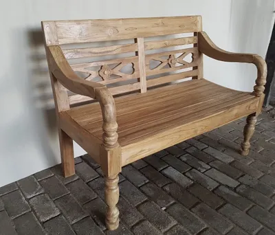 A wooden garden bench is shown against a light-colored wall and a brick floor.
