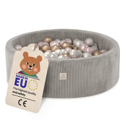 A grey corduroy ball pit filled with pink, gold, and white balls, with a tag attached.