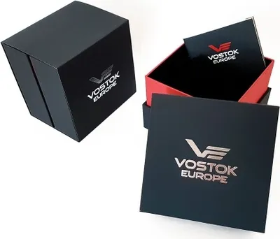 A black Vostok Europe watch box, open and closed, with its inner packaging and booklet.