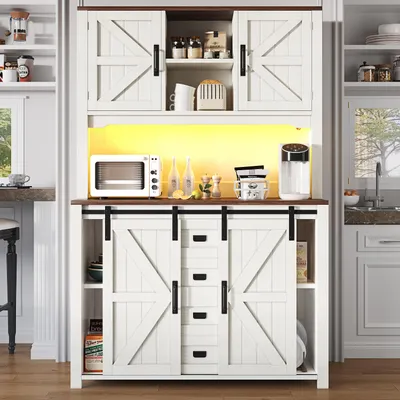 A white kitchen sideboard with sliding barn doors and drawers, featuring a microwave, water dispenser, and decorative items on top.