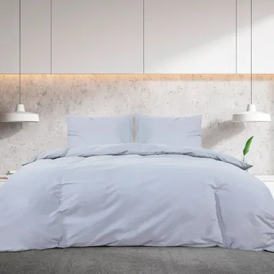 A bed with grey bedding in a modern bedroom.