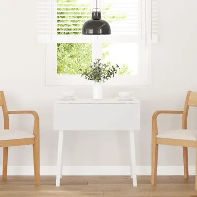 A white dining table with two chairs in a bright room with a window.