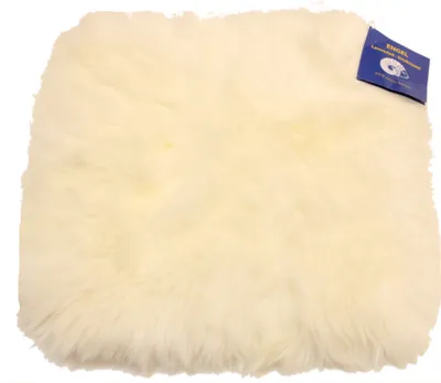 A cream-colored sheepskin seat cushion is shown against a white background. A blue tag with white text and a logo is attached to the upper right corner of the cushion.
