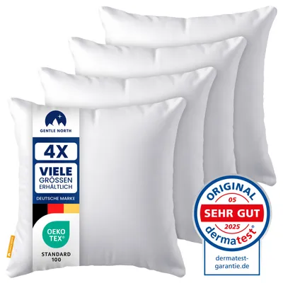 A stack of four white pillows, with a label on the front pillow.