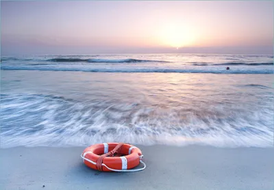 Produktbild von Wallario Fototapete Vliestapete, seidenmatte Oberfläche, einfache Verarbeitung, Größe 300 x 210 cm, Motiv Rettungsring am Strand bei Sonnenuntergang