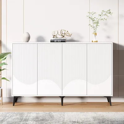 A white sideboard with a fluted design and curved accents on the doors, placed in a room with a plant and decorative items on top.