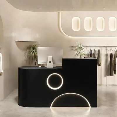A modern store interior with a reception desk and clothing racks.