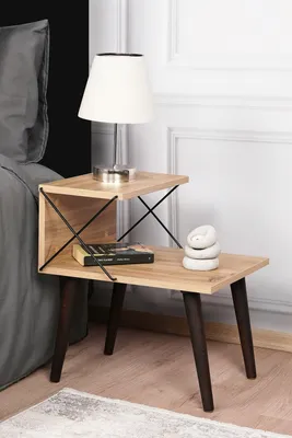A bedside table with a lamp, book, and decorative stones.