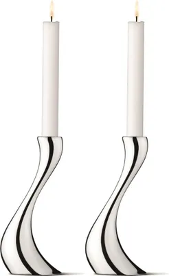 Two silver candleholders with white candles, lit.