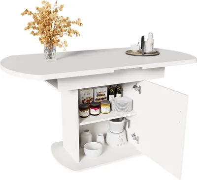 A white oval dining table with storage cabinets underneath, featuring jars, plates, and a small appliance. A vase with dried flowers is on the tabletop.