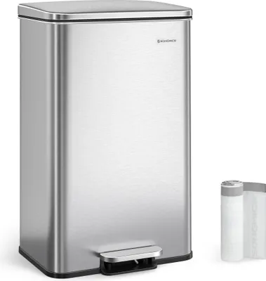 A stainless steel kitchen trash can with a foot pedal is shown against a white background. Two rolls of trash bags are placed to the right of the trash can.