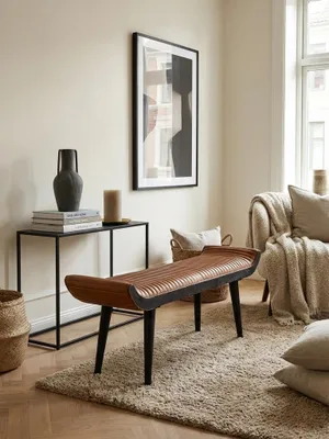 Sitzbank aus Echtleder in Cognac-Braun, stilvoll platziert in einem hellen Wohnzimmer mit Parkettboden. Die 125 cm lange Bank dient als eleganter Blickfang._#sku_SAFWL6.014#