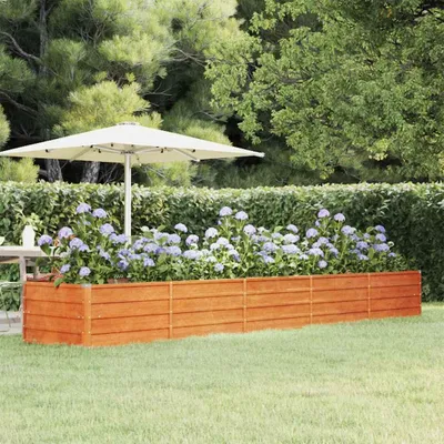 A raised garden bed filled with hydrangeas in a backyard setting with a patio umbrella.