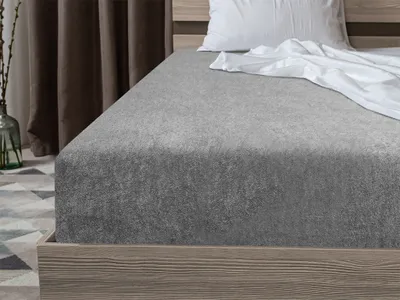 A close-up view of a grey fitted sheet on a bed.
