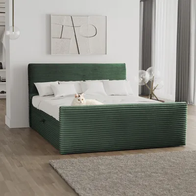 A green corduroy bed with white pillows and a white cat lying on it, in a modern bedroom setting with artwork on the wall and sheer curtains.