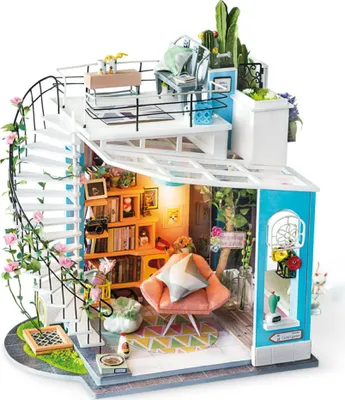 A miniature dollhouse with a spiral staircase, balcony, and interior rooms filled with furniture and plants.