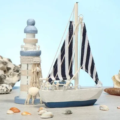 Image de Ensemble de décoration maritime Unyqoos®, 2 pièces – Bateau à voile et phare en bois, bleu et blanc, aspect vieilli. Dimensions : bateau 10 x 15,5 x 2,5 cm, phare Ø5 x H13 cm. Matériaux : bois/lin