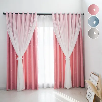 A pair of pink, double-layered curtains with sheer white overlays, decorated with small stars, are displayed in a room setting. The curtains are tied back with the sheer fabric. A small framed picture and dried plants are visible in the background.