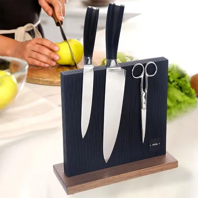 A person is cutting an apple in a kitchen, with a magnetic knife block holding knives and scissors in the foreground.
