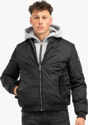 A man wearing a black bomber jacket over a gray hoodie.