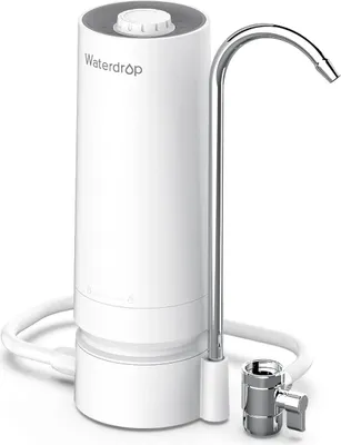 A white countertop water filter with a silver faucet and tubing.