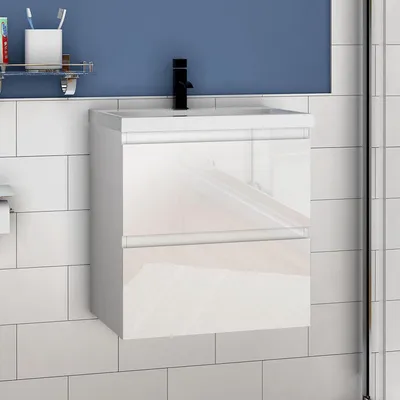 A modern bathroom vanity with a white ceramic sink and a high-gloss white MDF cabinet, set against a tiled wall and a blue background.