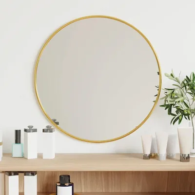 A round mirror with a gold frame is displayed on a shelf with various cosmetic products.
