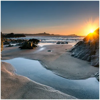 Produktbild von Wallario Premium Glasbild, freischwebende Optik, kräftige Farben, Größe 30 x 30 cm Motiv Sonnenuntergang hinter einem Felsen am Strand
