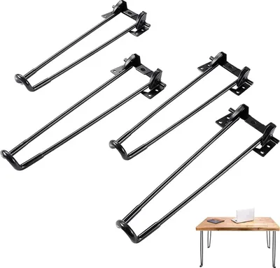 Four black metal table legs are arranged diagonally on a white background, with a small wooden table with a laptop and a book in the bottom right corner.
