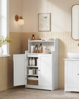 A white bathroom cabinet with doors open, displaying shelves with toiletries and storage baskets, in a bathroom setting with tiled walls and a wall lamp.