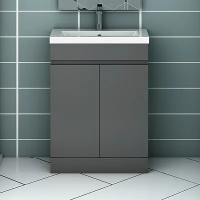 A dark gray vanity cabinet with a white sink and faucet, set against a tiled wall and floor.